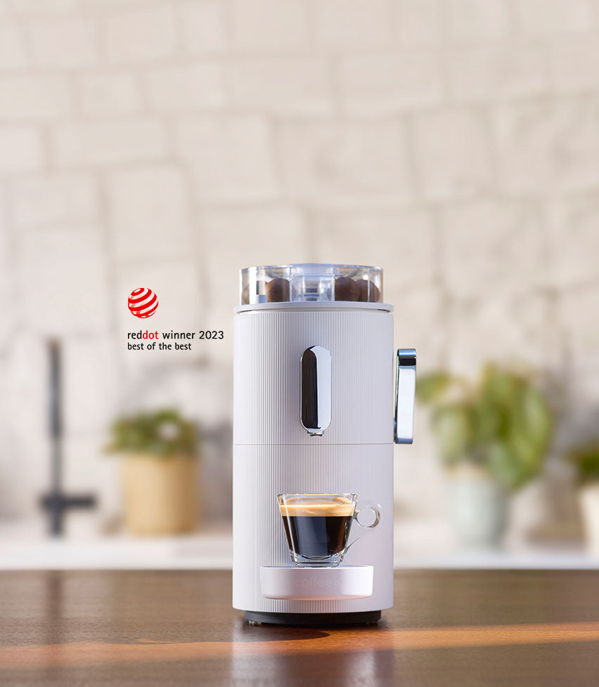 Eine weisse CoffeeB Kaffeemaschine mit einem Reddot Award Logo daneben